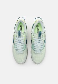 Jasnozielone i białe sneakersy z wzorem w kratę, siateczkową tkaniną i akcentami koloru morska zieleń. Sznurowane jasnoniebieskimi sznurówkami, z wyściełanym kołnierzem.