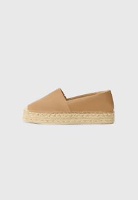 Tan-värinen nahkainen espadrilles-kengät pyöreällä varpaalla ja juuttiköydestä valmistetulla pohjalla. Muotoilu on sileä ja minimalistinen.