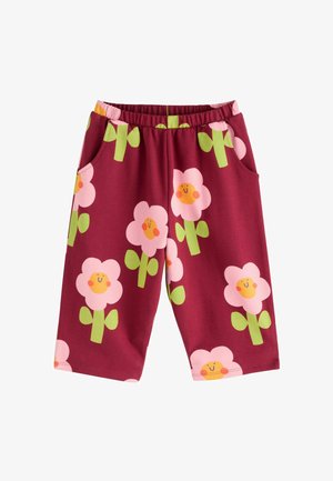 Burgundy shorts with elastic waistband featuring large pink flowers with smiling yellow faces and green stems, two side pockets, cotton fabric.