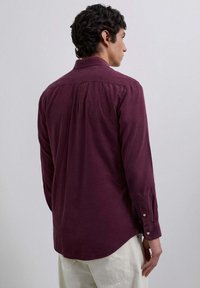 Burgunderfarbene Hemd mit Knöpfen und strukturiertem Finish, mit spitzem Kragen und Knopfmanschetten, von hinten präsentiert.
