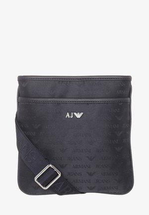 Czarna torba na ramię Armani Jeans z regulowanym paskiem, srebrnym logo orła AJ oraz subtelnym, powtarzającym się wzorem napisu Armani Jeans na tkaninie.