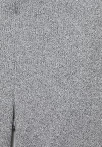 Grauer Strickstoff mit strukturierter, gerippter Oberfläche und einem Schlitzdesign entlang des Randes, der verschiedene Grautöne aufweist.