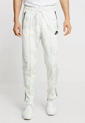 Weiße Jogginghosen mit floralem Muster, tailliertem Design, elastischem Bund, Kordelzug, seitlichen Taschen und schwarzen Nike-Logo-Akzenten.