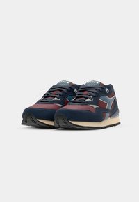 Navy and burgundy athletic shoes with textured upper, laces, and a visible sole. Positioned on a white background.