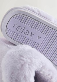 Pantofole color viola chiaro con una texture soffice, dotate di un collo imbottito e una suola in gomma con la scritta "relax", che evidenziano comfort e aderenza.
