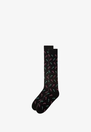 Black cotton socks featuring a repeating pattern of red and green candy canes. Smooth texture with a knee-high design.