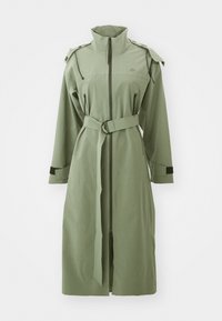 Cappotto verde di lunghezza media realizzato in tessuto leggero, caratterizzato da un alto colletto, chiusura con zip, cintura e spalline.
