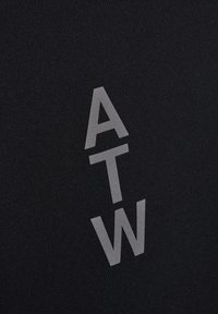 Zwarte stof met een verticale rangschikking van de letters "A," "T," en "W" in een vet, lichtgrijze lettertype. Gladde textuur.