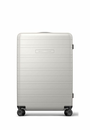 Silver hard-shell suitcase with horizontal grooves, retractable handle, and four black spinner wheels on a white background.