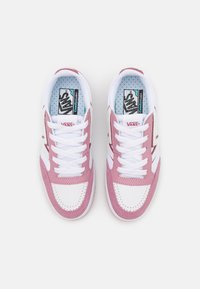 Rosa og hvite joggesko med en glatt lær- og mesh-finish, med en perforert tåboks, snøring, og en merket innersåle.