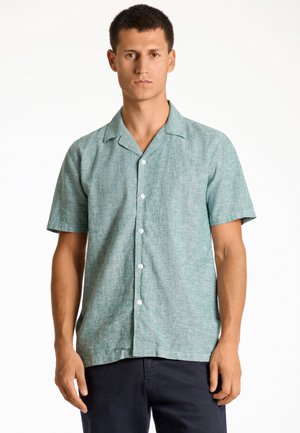 Camisa de manga corta, con botones, en mezcla de lino verde claro. Presenta un sutil patrón texturizado y un cuello con muesca.