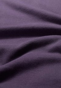 Fialová bavlněná tkanina s hladkou texturou, ukazující jemné záhyby a vrásky, nabízející soudržnou, konzistentní barvu po celé ploše.