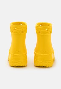 Stivali in gomma gialla con accenti testurizzati, aperture rotonde alla caviglia e suola a righe. Presenta il logo impresso sul retro.