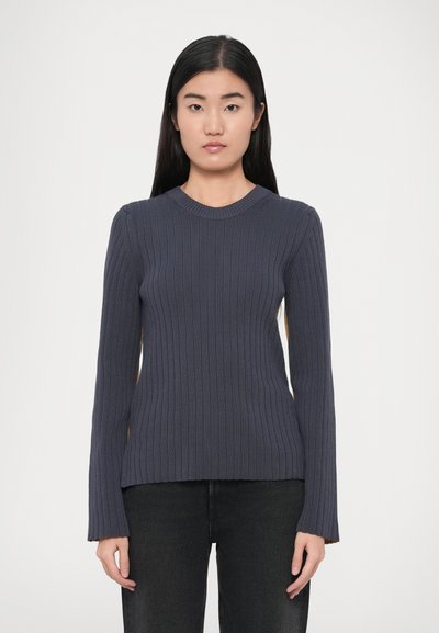 Pull bleu marine côtelé à manches longues et col rond. Présente une silhouette ajustée et un motif en tricot texturé. Associé à un pantalon noir.
