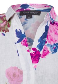 White linen blouse featuring a floral pattern in pink, purple, and green, with a classic collar and a subtle V-neckline. Size tag visible.