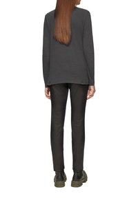 Zwarte lange mouwen shirt met eenRelaxte pasvorm en een ronde halslijn, gecombineerd met strakke zwarte broek en chunky zwarte laarzen met groene zolen.