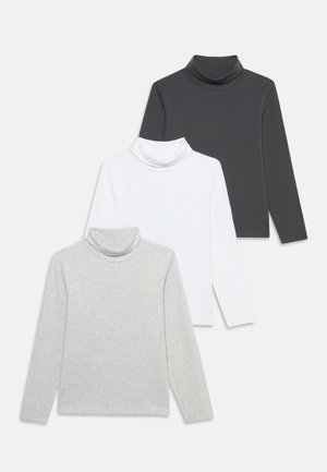 Trois hauts à manches longues et à col montant, de couleur anthracite, blanche et gris clair, disposés en se chevauchant sur un fond uni.