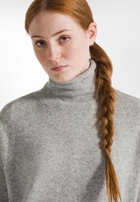 Grauer Rollkragenpullover aus weichem Strickmaterial mit lockerer Passform. Verfügt über einen hohen Kragen und strukturierte Stoff.