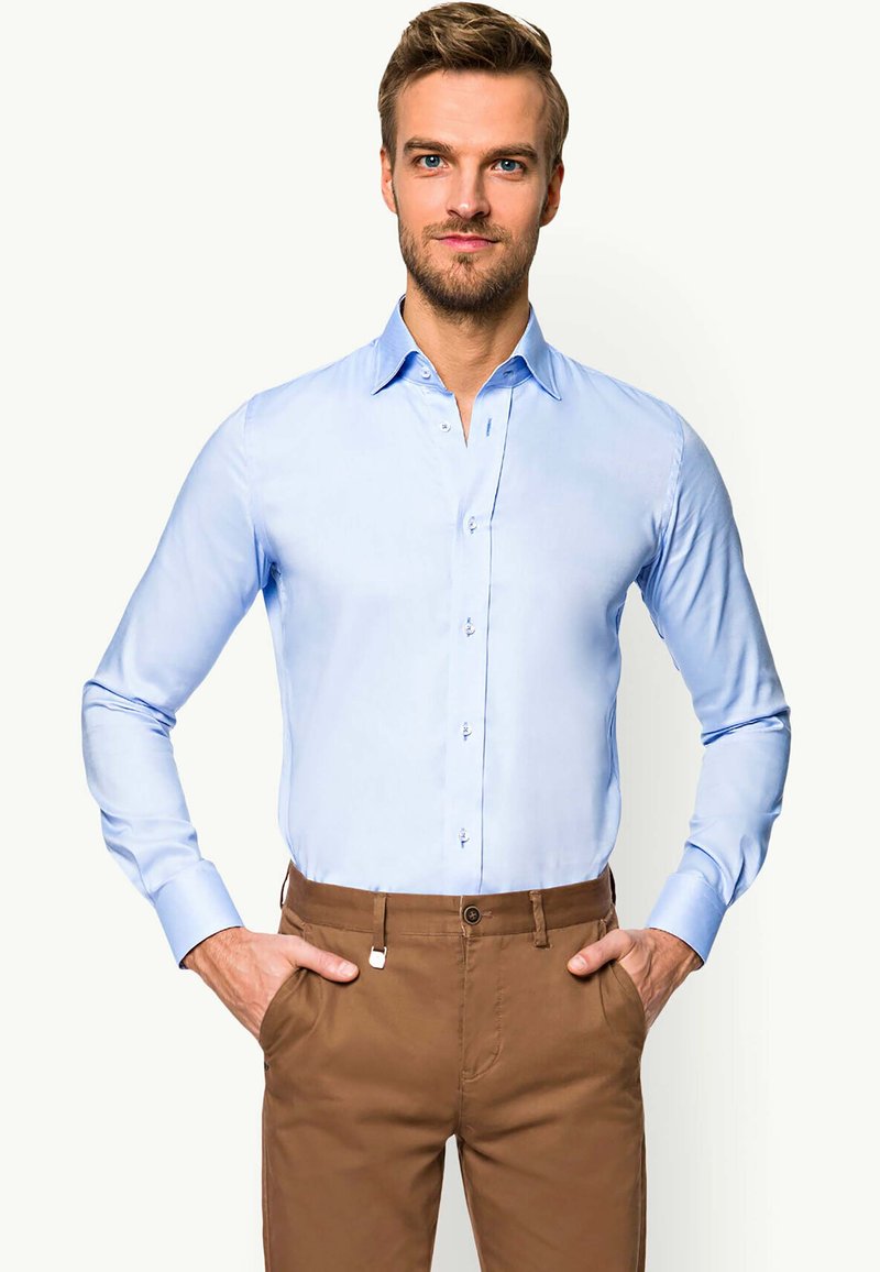 Jasnoniebieska koszula na długi rękaw z guzikami, z kołnierzykiem typu point, dopasowanym krojem, gładką teksturą i kontrastowymi guzikami, zestawiona z brązowymi spodniami.