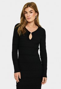 Robe noire en maille côtelée à manches longues et décolleté en forme de goutte. Présente une silhouette ajustée et un motif texturé sur l'ensemble.