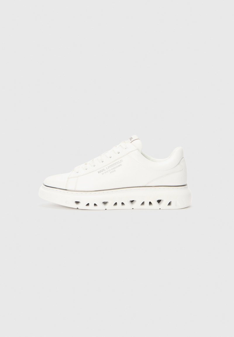 Sneaker in pelle bianca con punta rotonda, dettaglio laterale testurizzato e suola rialzata con fori di ventilazione. Branding discreto sul lato.
