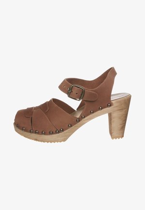 Hnědé semišové sandály na vysokém podpatku s otevřenou špičkou, přezkou a ozdobnými kovovými hroty podél dřevěné platformy a podpatku.