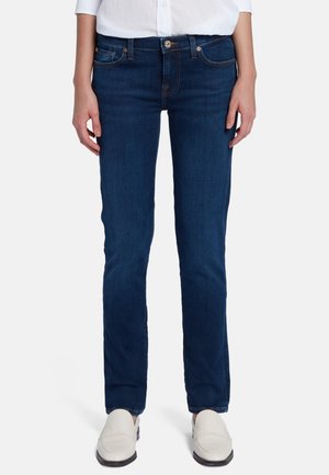 Donker gewassen denim jeans met een slim fit, lichte stretch, vijf zakken, gouden stiksels en een voorknopsluiting, gecombineerd met witte schoenen.
