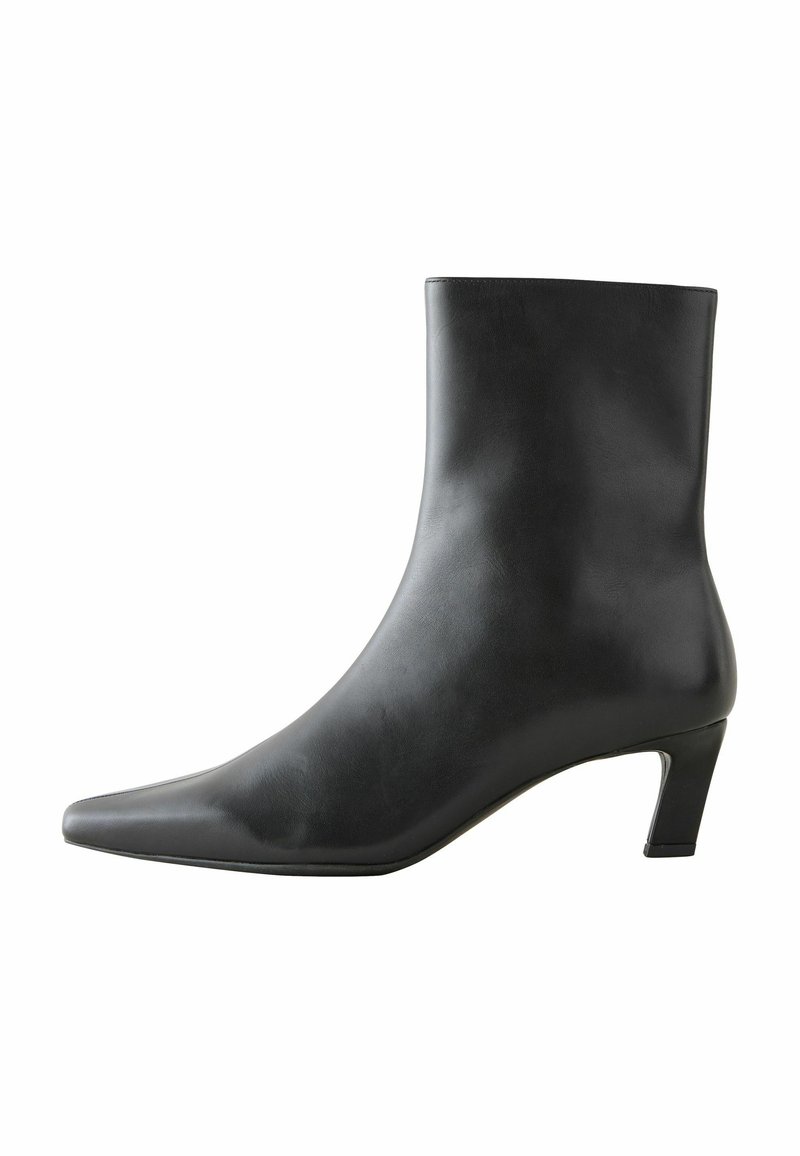 Stivaletto in pelle nera con punta affusolata e tacco di altezza media. Texture liscia, design elegante e stile minimalista.