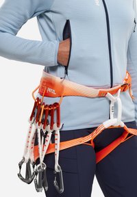 Das Geschirr verfügt über einen orange-weißen verstellbaren Gurt, der mit mehreren roten Karabinerhaken, angebrachten Riemen und einem strukturierten hellblauen Oberteil ausgestattet ist.