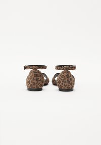 Leopard print flats with a soft suede texture, adjustable ankle straps, low black heels, and cut-out side details.