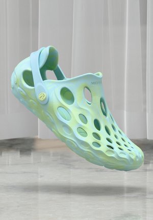 Zoccoli leggeri realizzati in materiale morbido e flessibile, con una sfumatura di blu chiaro e verde. Presentano un design traforato e una fascia regolabile.