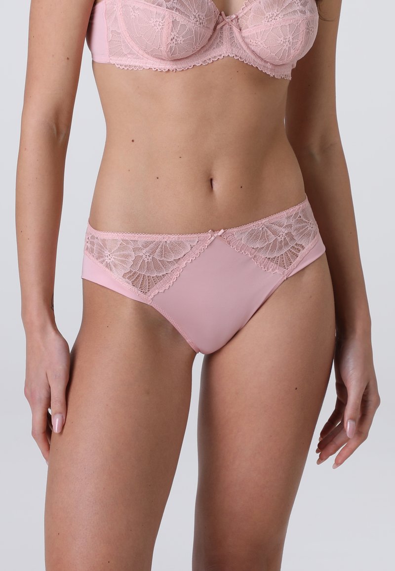 Slip in pizzo rosa e raso con dettagli in pizzo floreale in vita, caratterizzato da una finitura liscia e un piccolo fiocco centrale.