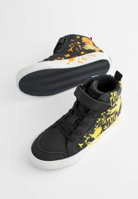 Hoge sneakers van zwart synthetisch materiaal met een gele spetterpatroon. Voorzien van een klittenbandsluiting en een getextureerde rubberen zool.