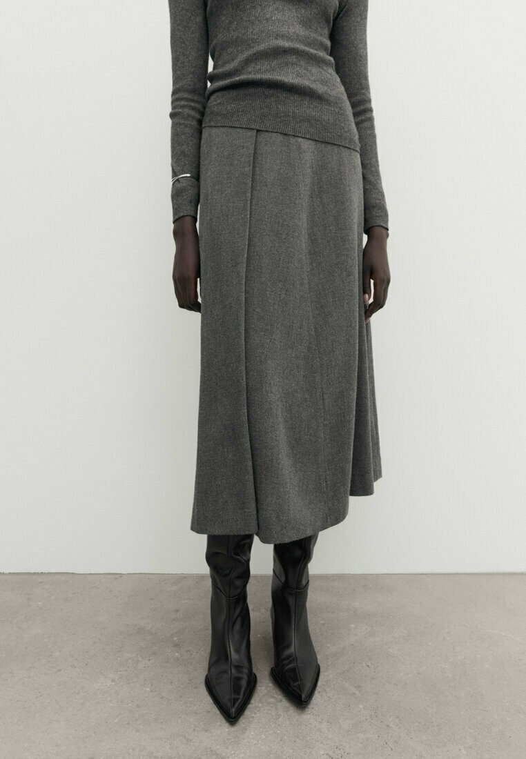 Grå ullblandning midi kjol med rak skärning och subtila veck, kombinerad med eleganta svarta spetsiga ankelskor. Strukturerad stickad tröja.