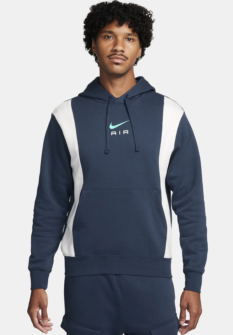 Hanorac bleumarin cu panouri laterale albe, cu glugă cu șnur și buzunar frontal tip kangaroo. Prezintă un logo Nike în nuanța teal cu textul "AIR" dedesubt.