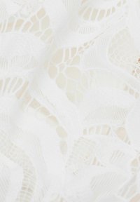 Vitt spetsmaterial med ett blommönster som har upphöjda texturer och ett slätt, genomskinligt utseende, som visar upp intrikata detaljer genom hela tyget.