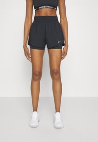 Zwarte sportieve shorts met een aansnoerbare taille en binnenvoering, met een klein wit logo. Gecombineerd met witte sneakers.
