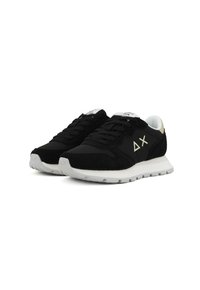 Scarpe sportive nere con tomaia in suede e tessuto, caratterizzate da suola in gomma bianca, lacci neri e dettaglio del logo sul lato.