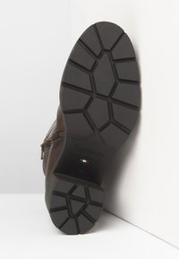 Semelle de botte en cuir marron avec un motif de semelle géométrique, fermeture éclair latérale et texte "NeroGiardini Fabriqué en Italie" en relief.