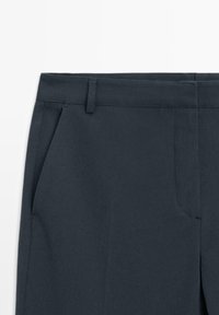 Donkerblauwe pantalon met een platte voorkant, twee zijzakken en een gladde textuur. Heeft een slim fit en een strakke, op maat gemaakte uitstraling.