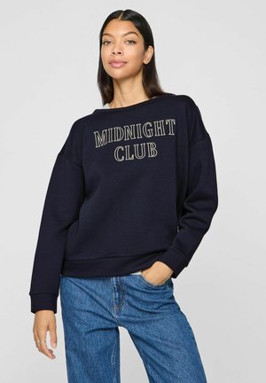 Sudadera azul marino con "MIDNIGHT CLUB" en texto crema en contraste, hecha de un material suave con un corte relajado y puños de canalé.