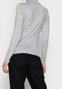 Grå polotröja med långa ärmar, ribbad halsringning och mudd, figursydd design, matchad med svarta byxor, visande bakvy.
