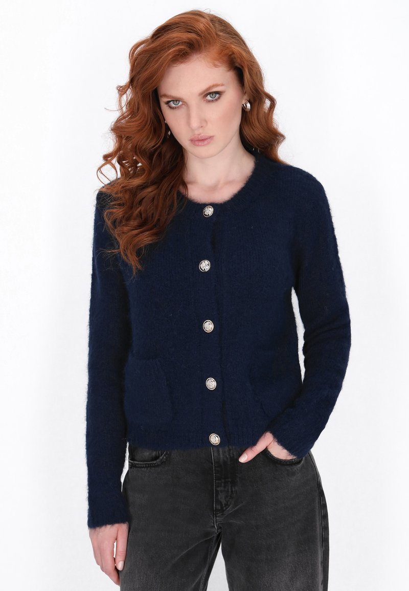 Marineblauwe cardigan van zacht, gestructureerd materiaal, met een ronde halslijn, twee voorzakken en vijf decoratieve zilveren knopen.