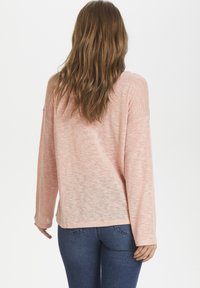 Jasnoróżowy sweter z długim rękawem o luźnym kroju, wykonany z teksturowanej tkaniny. Posiada okrągły dekolt i obniżone ramiona.