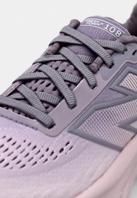 Purple athletic shoe with a breathable mesh upper, textured accents, flat laces, and a cushioned sole. Features a logo on the tongue and side.