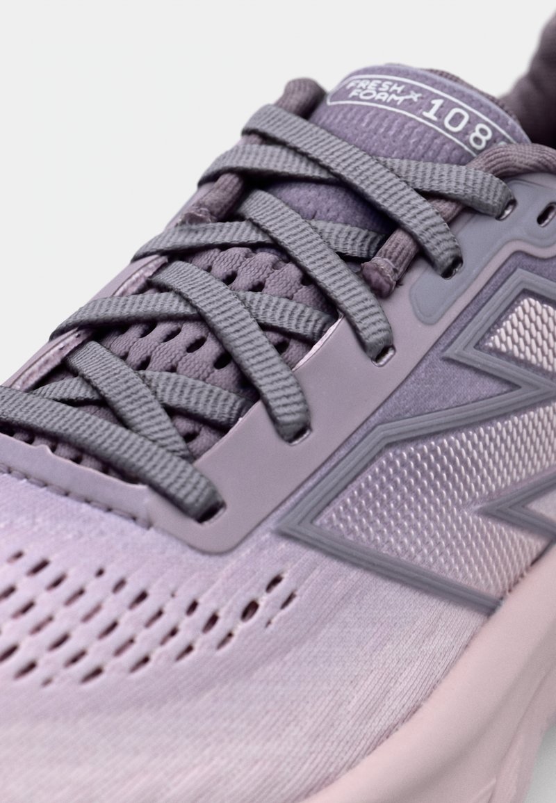 Baskets de sport violettes avec une tige en mesh respirant, des accents texturés, des lacets plats et une semelle rembourrée. Présente un logo sur la languette et le côté.