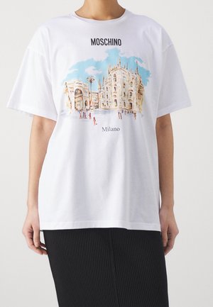 Osoba nosząca białą koszulkę Moschino z kolorową ilustracją katedry w Mediolanie oraz okolicznych budynków.