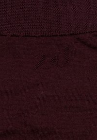 Tejido de punto burdeos con una textura suave. Presenta un patrón sutil, con el número "20" estampado cerca del borde inferior.