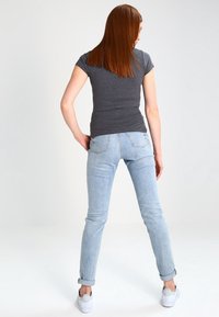 Gråta anpassad T-shirt och ljusblå jeans med uppvikta ärmar, i kombination med vita sneakers. Slät textur, avslappnad passform och minimala designdetaljer.