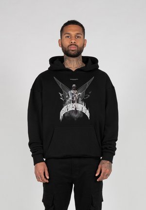 Schwarzer Kapuzenpullover mit einem grafischen Druck, der eine Figur mit Flügeln und Text zeigt. Baumwollmaterial, lockere Passform, Vorderseite Tasche und gerippte Bündchen.